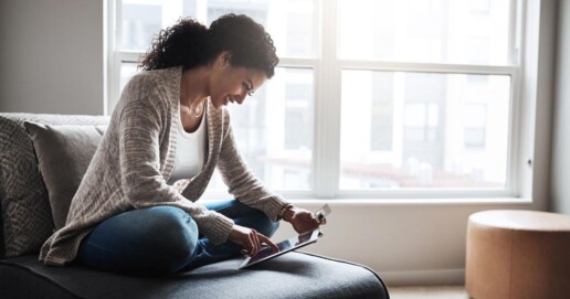 Eine Frau sitzt auf einem Sessel und schaut auf ein Tablet